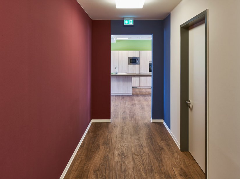 Farbige Wandflächen aus dem Farbkanon der Wohnanlage unterstützen die Orientierung.