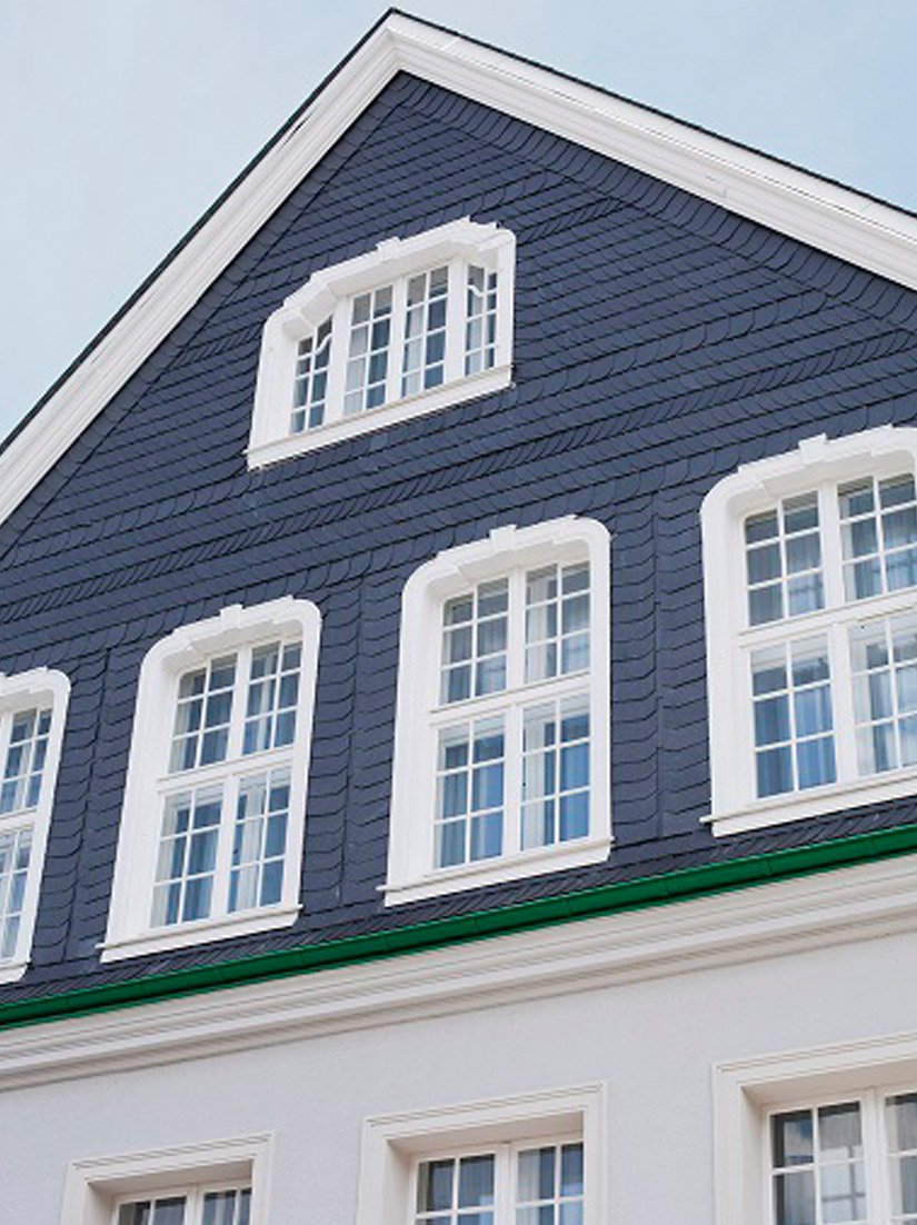 Die Außenfassade des 1915 gebauten Schulhauses mit ihren für die Region typischen Schieferschindeln, dem repräsentativen Erker und den Regenrinnen im Farbton Bergischgrün wurde bei der Restauration erhalten.