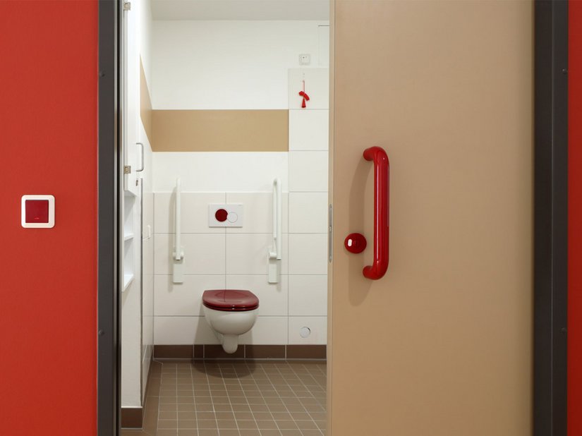 Rot gilt in der Demenz- und Geriatrieforschung als überdurchschnittlich gut wahrnehmbare Farbe: Rote Türbeschläge, der rote Toilettendeckel und der Spülknopf gewährleisten die schnelle Auffindbarkeit des WCs.