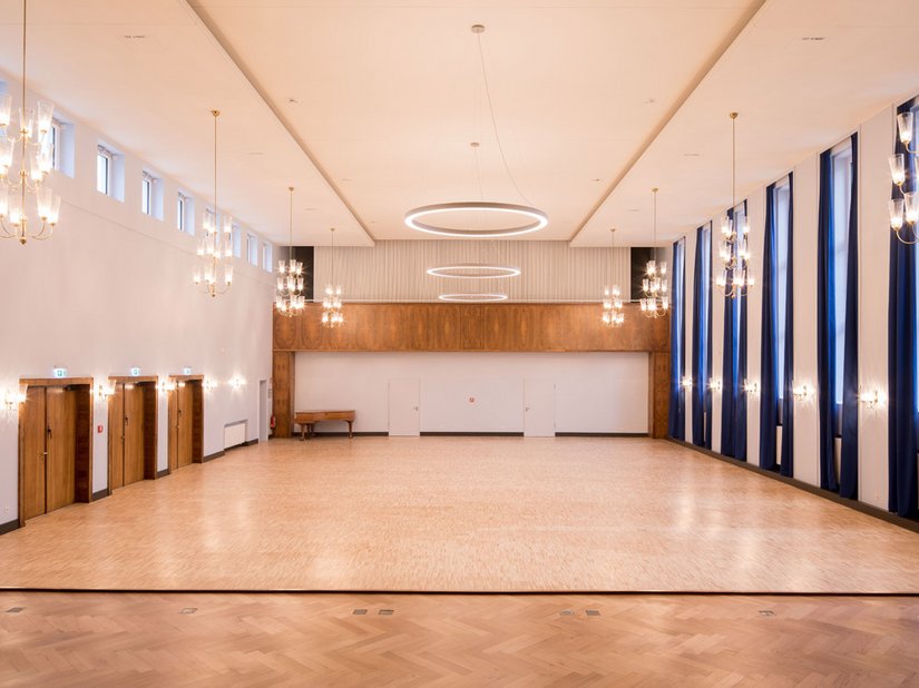 Die restaurierten goldenen Hänge- und Wandleuchten im Collenbachsaal wurden mit drei großen, modernen LED-Ringpendelleuchten ergänzt.