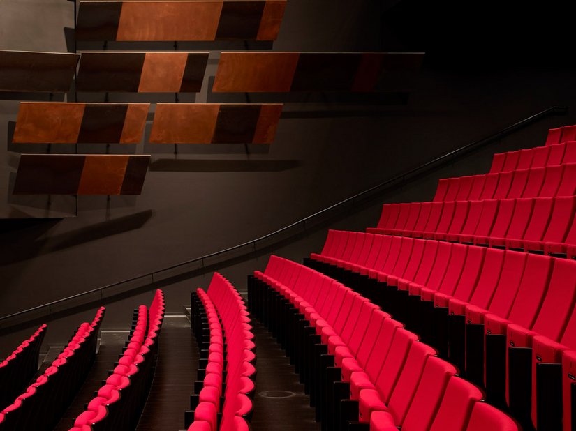 Die roten Sitze heben sich stark aus dem sonst dunkel gestalteten Theatersaal hervor.