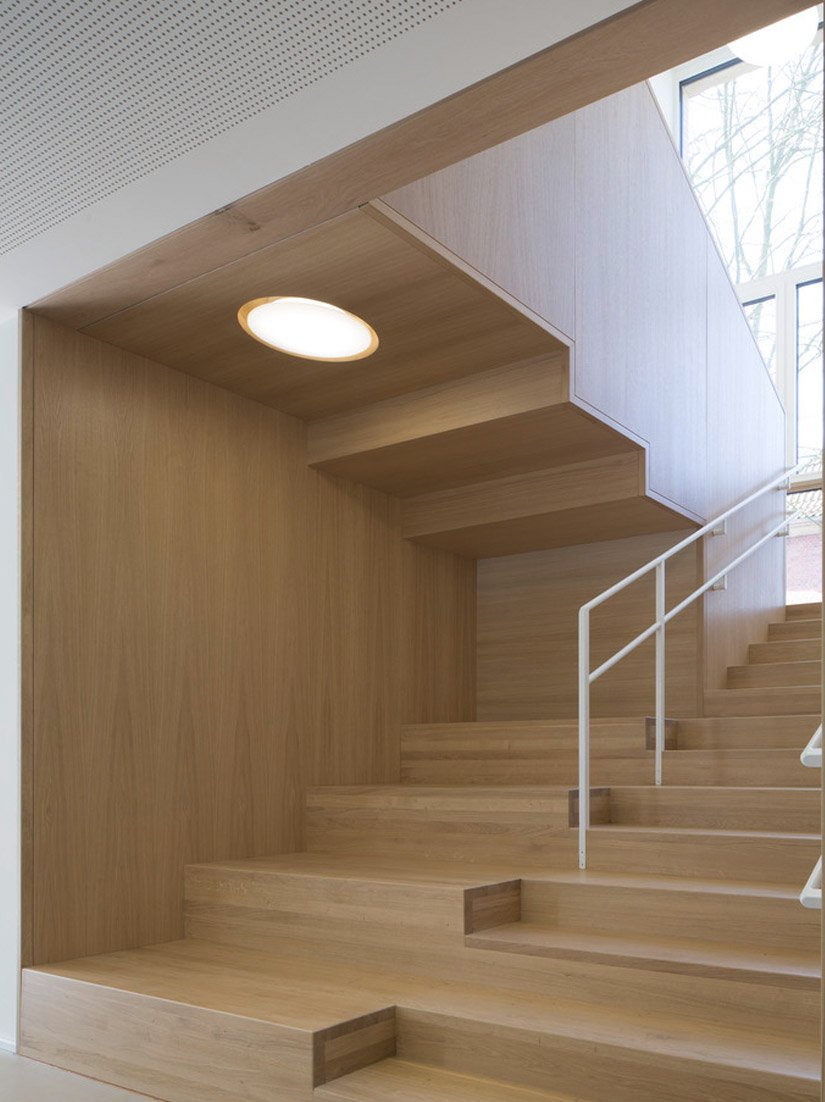 Die Holztreppe sticht aus der sonst hellen Gestaltung hervor.