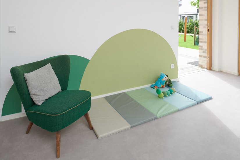 Ein pastellfarbenes Wandmotiv in Anlehnung an eine Weide. In einem dezenten Grün schuf die Paul Schulze Malerbetrieb GmbH den Farbakzent in einem ansonsten weißen Gruppenraum.