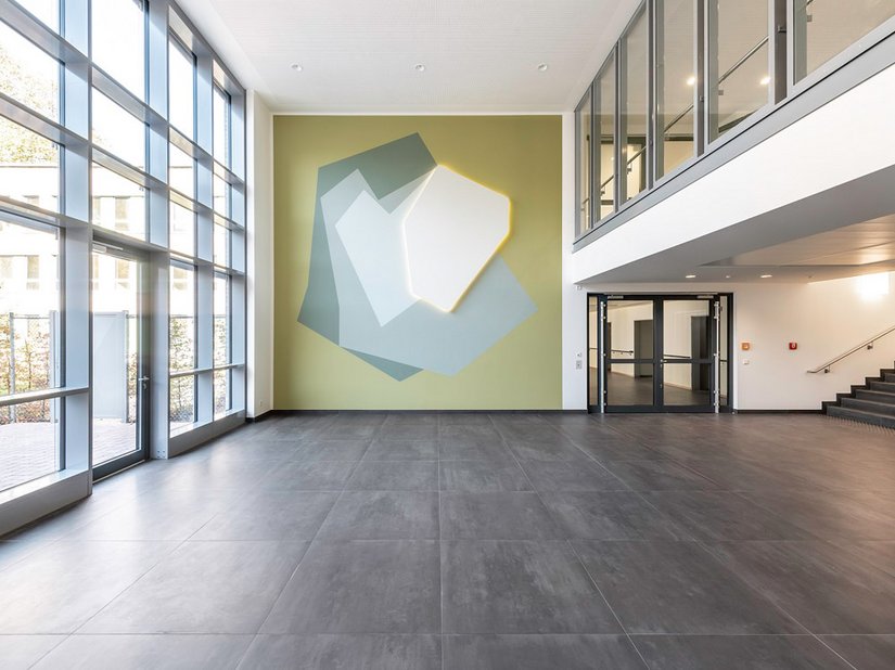 Die Wandarbeit „Lichtung“ von Caroline Bayer prägt das Foyer des neuen Hauptgebäudes der LWL-Klinik Münster mit einer sanften, naturbezogenen Ästhetik.