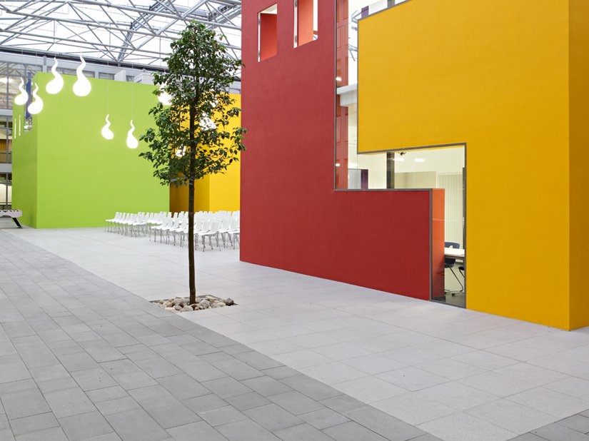 <p>Gepflanzte Bäume und die Farbgestaltung lockern die Atmosphäre im Innenhof der Schule auf.</p>