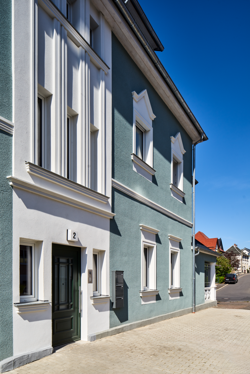 Wechsel aus Flächengestaltung und raffinierten Details: Das gebrochene Weiß und der petrolfarbene Grundton wechseln sich elegant ab und machen das Mehrfamilienhaus an der Karl-Liebknecht-Straße 2 in Suhl zu einem Hingucker.