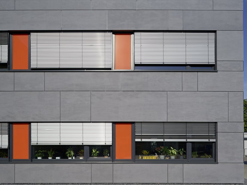 <p>Die hinterlüftete Fassade aus Faserzementplatten ist in lichtem Grau gestaltet.</p>