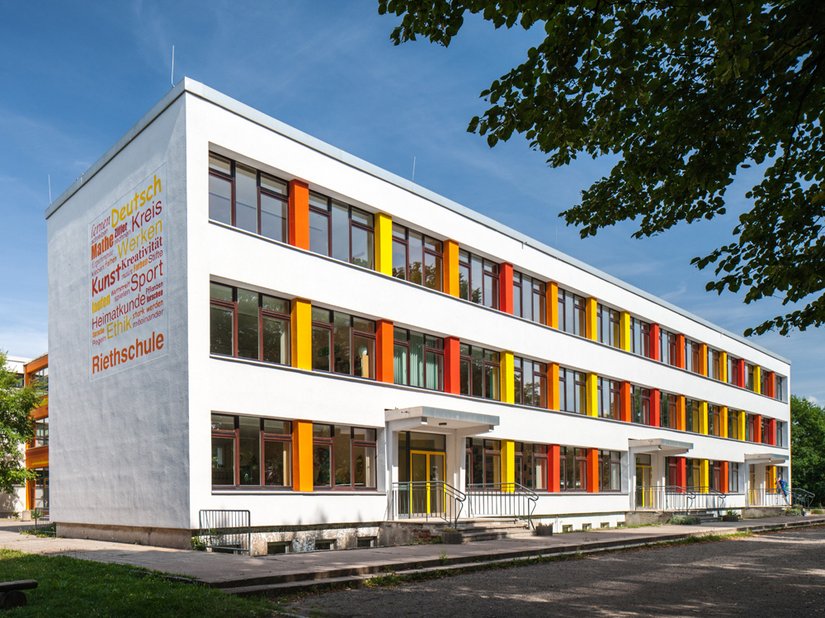 <p>Heute wird die weißgraue Fassade durch farbige Akzente gegliedert.</p>