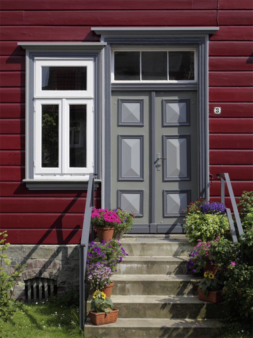 <p>Das Betongrau der Haustür harmoniert sowohl mit den übrigen Farbgebungen als auch mit dem Sockel aus Naturstein.</p>