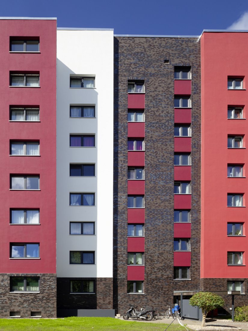 Das Konzept lebt von der Spannung zwischen der Farbigkeit der dunkel glänzenden Keramik und der kräftig farbigen Putzflächen in Rot, im Zusammenspiel mit neutralen Tönen wie Grau und Weiß.