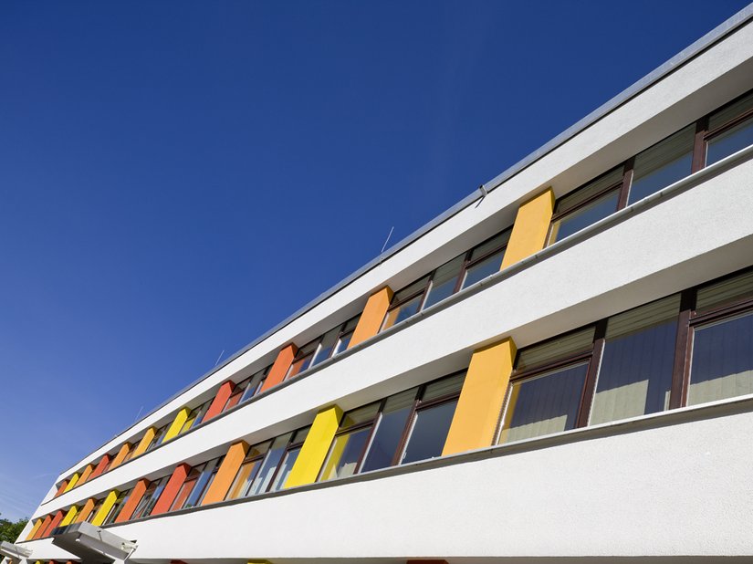 <p>Die braunen Fensterrahmen verfließen nahtlos in der Fassade.</p>