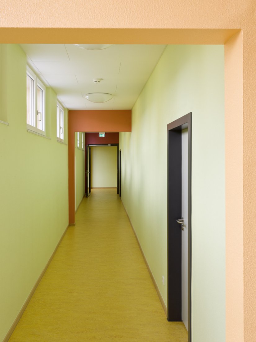<p>Durch den Farbverlauf wird der laubengangähnliche Durchgang zu den Klassenräumen bzw. zu der Verwaltung zu einem kurzweiligen Farberlebnis.</p>