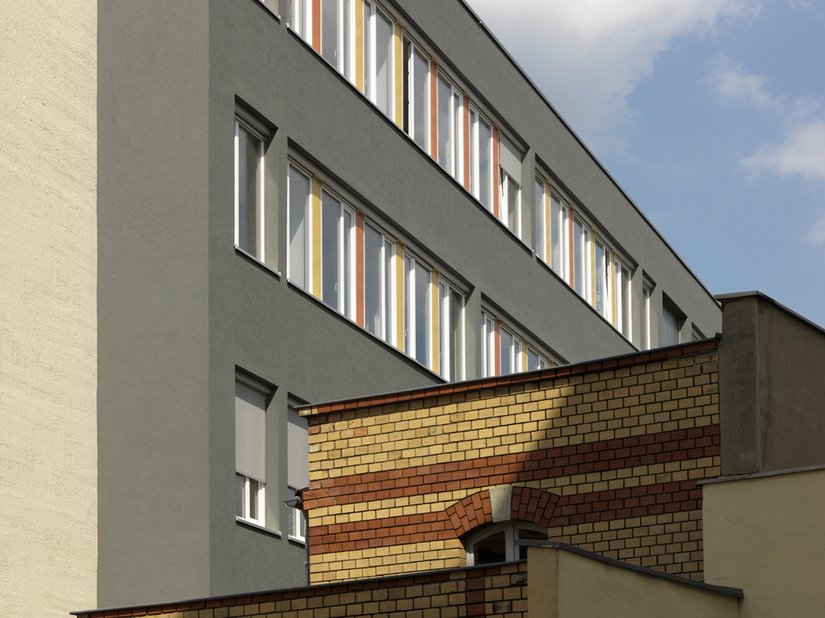 <p>Die Klinkerfarben Ziegelrot und Rotorange tauchen in den vertikalen Farbstreifen der Fensterbänder des sanierten Neubaus wieder auf.</p>