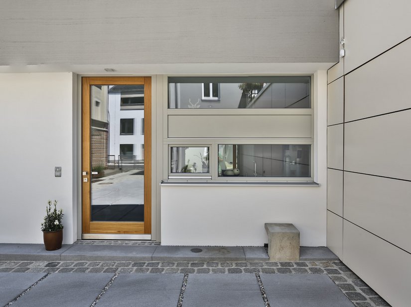 <p>Das helle Holz der Haustür setzt sich deutlich vom einheitlichen Grau ab.</p>