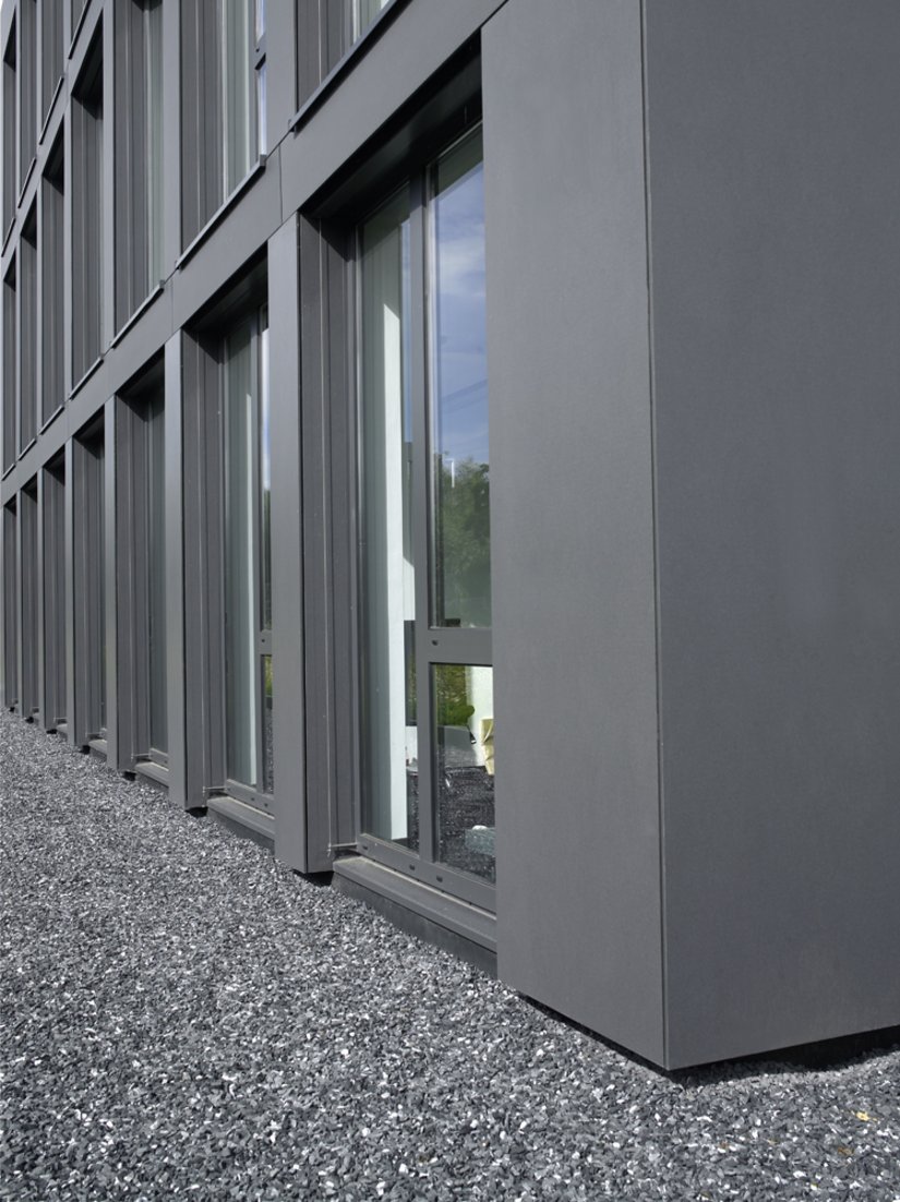 <p>Die natürlich grauen Kieselsteine vor dem Bürogebäude runden das einheitliche Erscheinungsbild im Übergang zur Außenwelt ab.</p>