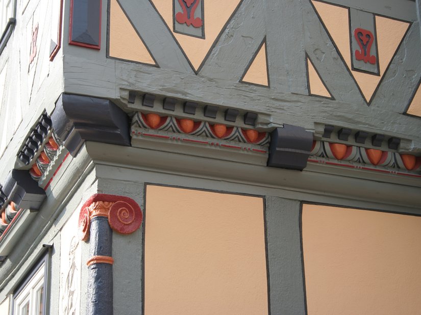 <p>Die ocker-orangefarbene Gefachefarbigkeit nimmt die ortstypische Farbigkeit der Begleitstriche in abgewandelter Form wieder auf, integriert das Gebäude ins Gesamtensemble und ihm die ihm gebührende Wertigkeit und Betonung innerhalb des Innenstadtbereiches.</p>