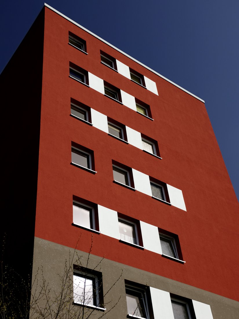 <p>Der hohe Sockel in dunkler Sandkalkputzfarbe kontrastiert wunderbar mit den aufgehenden Geschossen in Ziegelrot.</p>
