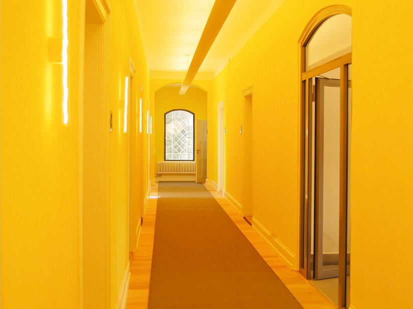 <p>Gelb versinnbildlicht als ausstrahlende Farbe die Kommunikation. Die intensiv gelbe Lasur der Flure nimmt diese Gestaltungsidee auf.</p>