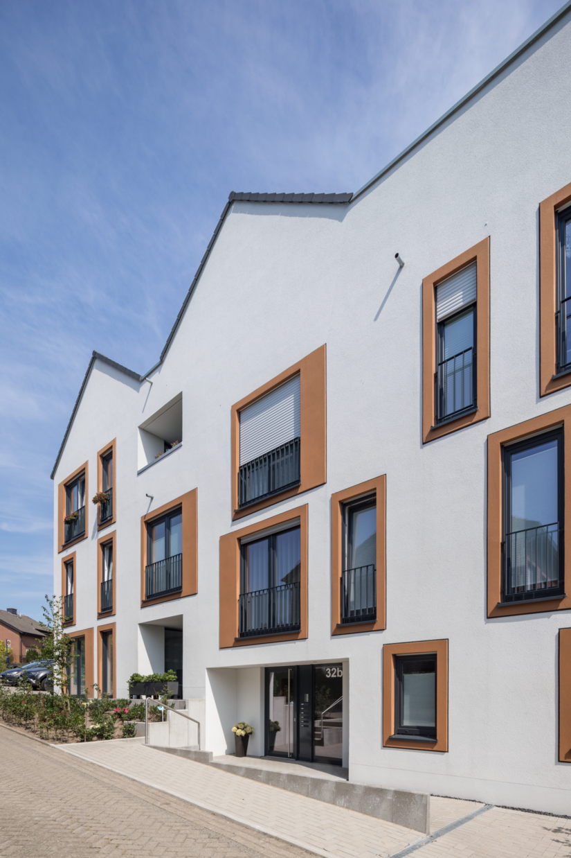 Um die plastische Wirkung der Einrahmung zu verstärken, wurden die Fensterfaschen in drei verschiedenen Brauntönen sowie mit einem Glattputz gestaltet und zusätzlich durch einen schwarzen Akzentstrich zwischen vorstehender Fensterfasche und Hauptfassade abgesetzt.