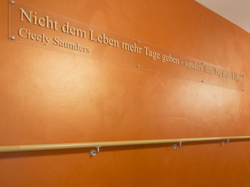 <p>Im Flurbereich gibt ein kräftiges Orange in einer Gestaltungstechnik mit Creativ Lucento 83 den Ton an und sorgt mit dem auf die Wand applizierten Sinnspruch für eine aufheiternde Stimmung.</p>