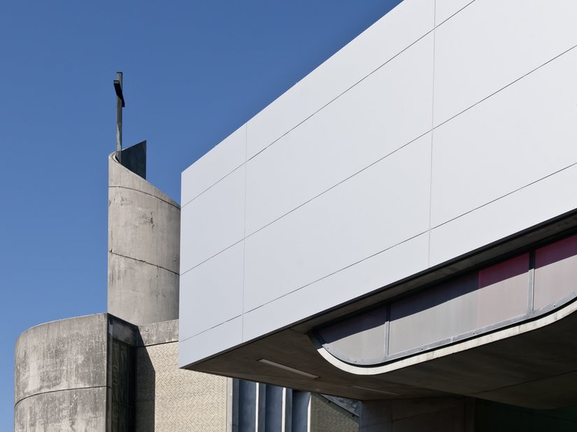 <p>Die „vertikale“ Fassade wirkt durch die homogene Verkleidung mit silbergrauen Aluminiumplatten fast wie eine Karosserie.</p>