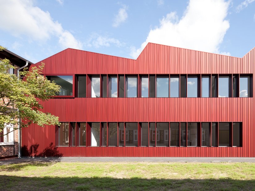 <p>Die rötlich eloxierte Aluminiumfassade orientiert sich an der Farbigkeit der Bestandsbauten.</p>