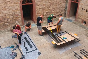 <p>Gemeinschaftswerk: Die Studierenden bauen ihre selbst konstruierten Stahlmöbel im Innenhof des Schlosses zusammen.&nbsp;</p>