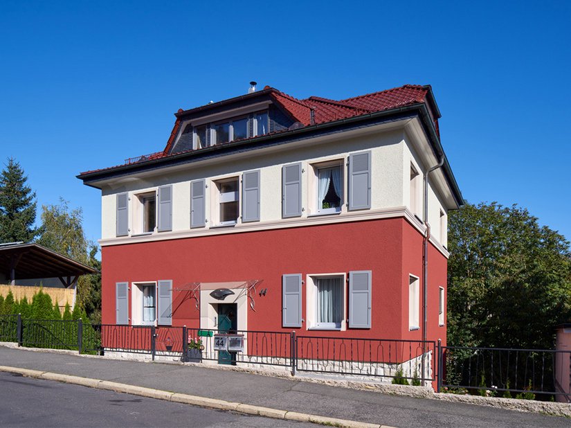 Farblicher Dreiklang: Sattes Rot in den unteren beiden Geschossen in Kombination mit Crème im Obergeschoss und an Fensterfaschen sowie dem Grau der Fensterläden. Das Brillux Farbstudio entwickelte ein individuelles Farbtonkonzept für das Mehrfamilienhaus in Meiningen.