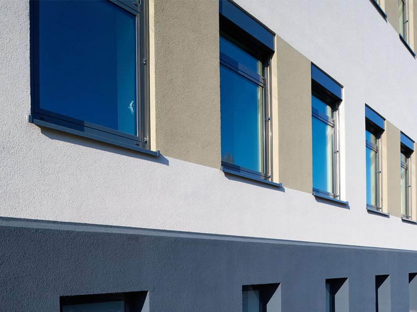 Dezente und zugleich moderne Oberflächengestaltung: Mit Evocryl 200 beschichtete die ZD Bau GmbH den Oberputz in verschiedenen Farbtönen. Um die große Fassadenfläche mit vielen kleinen Fenstern zu gliedern, erstellten sie Fensterspiegel in einem vergrauten Beigeton oder Taubenblau.
