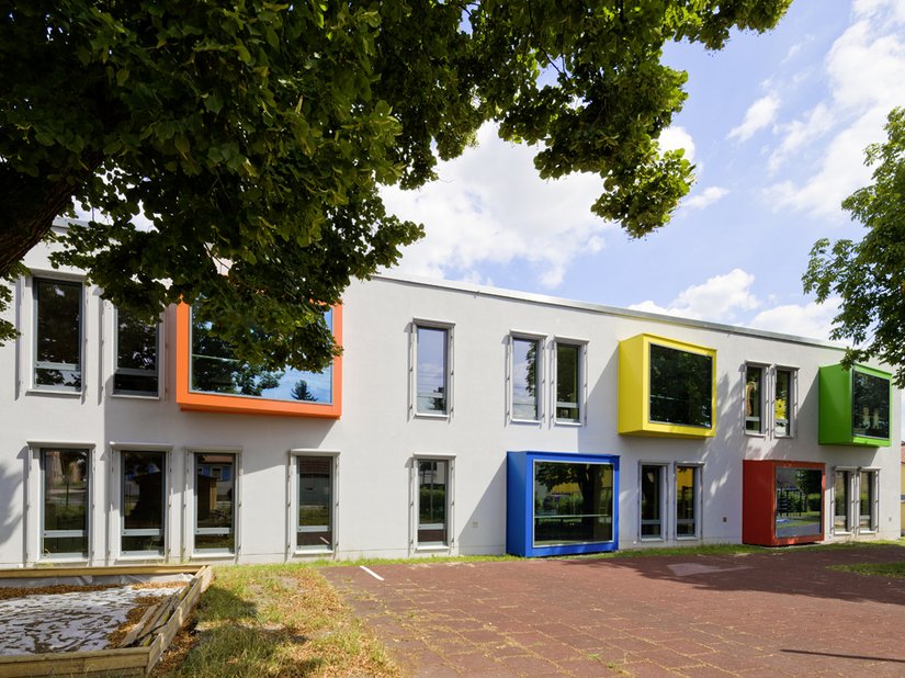 <p>Die straßenseitige Fassade wird von fünf Fensterkästen dominiert, die jeweils in einer kräftigen Farbe erstrahlen.</p>