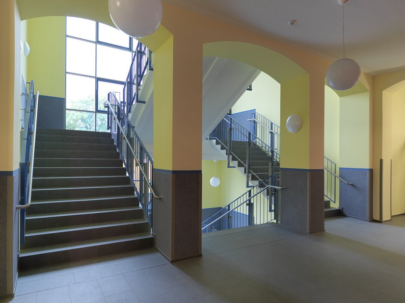 <p>Das Treppenhaus erhält durch die großen Fenster und den warmen Gelbton viel Helligkeit.</p>