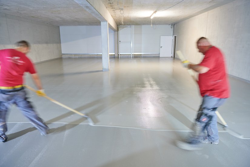 Nach dem Anmischen und Transport zum Ort der Verarbeitung: Zwei Personen verteilten gleichzeitig die Bodenversiegelung mit der Gummiflitsche und ermöglichten so einen zügigen Fortschritt.