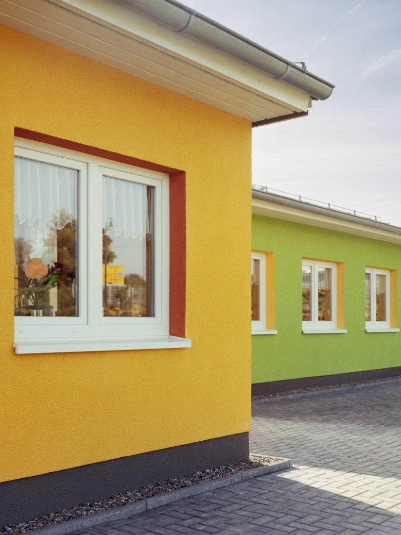 <p>Die Wandfarbe des linken ziert die Innenseite der Fensteraussparungen des rechts liegenden Gebäudes, sodass ein Zusammenspiel der Farben entsteht.</p>