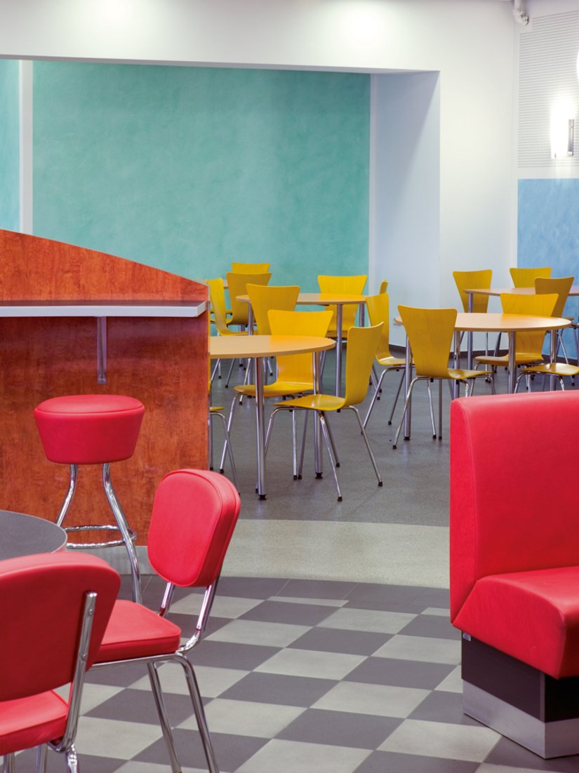 <p>Noch einmal Betriebsrestaurant Halle 1 Nord: Sie ist in unterschiedliche Farb- und Erlebnisbereiche zoniert. Diese Gliederung spiegelt sich in Bestuhlung, Innenarchitektur und auch der Fußbodengestaltung wider.</p>
